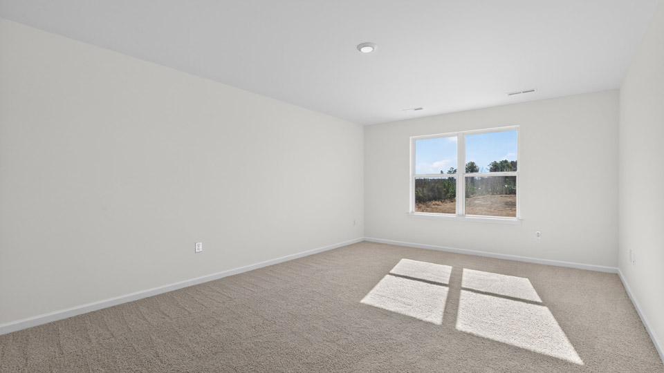 primary bedroom with two windows and carpeting, attached bath