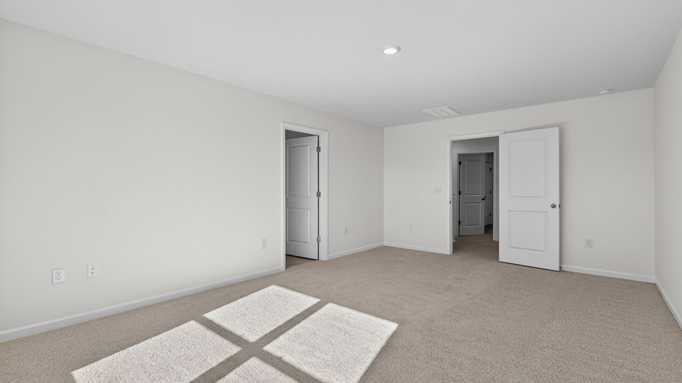 primary bedroom with two windows and carpeting, attached bath
