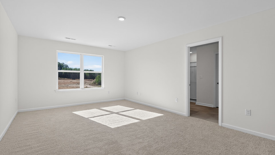 primary bedroom with two windows and carpeting, attached bath