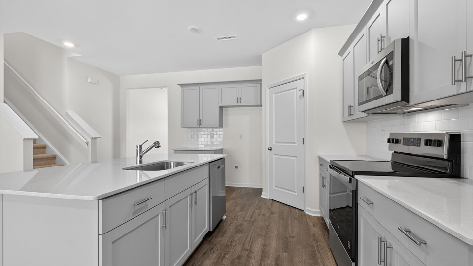 kitchen with quartz counters, kitchen island, pantry, stainless steel appliances