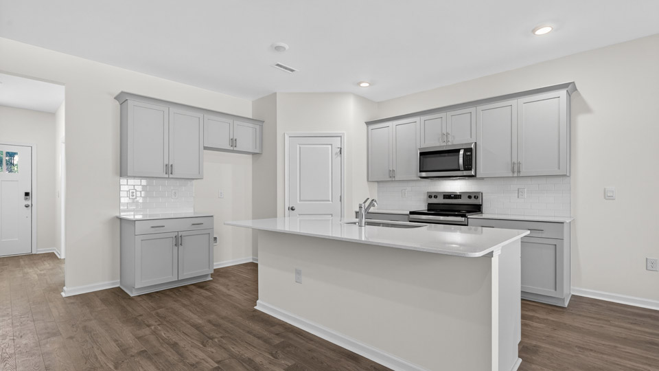 kitchen with quartz counters, kitchen island, pantry, stainless steel appliances