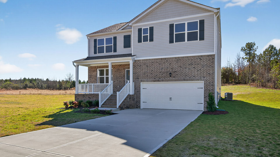 Two story home with white siding and covered porch and two-car garage.