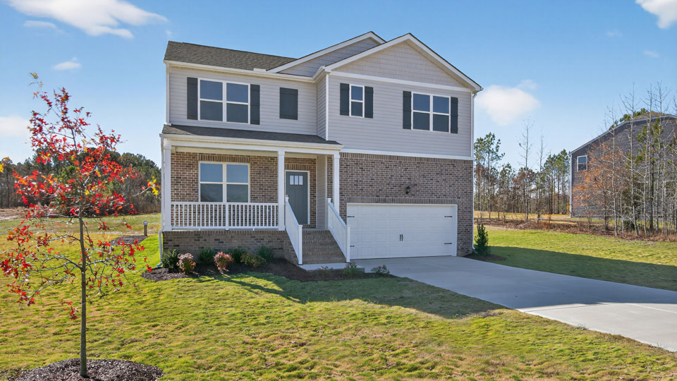 Two story home with white siding and covered porch and two-car garage.