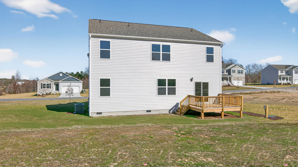 Two story home with white siding and back deck.