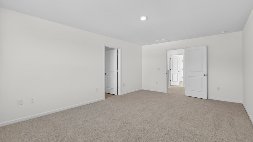 Primary bedroom with carpet and access to primary bathroom