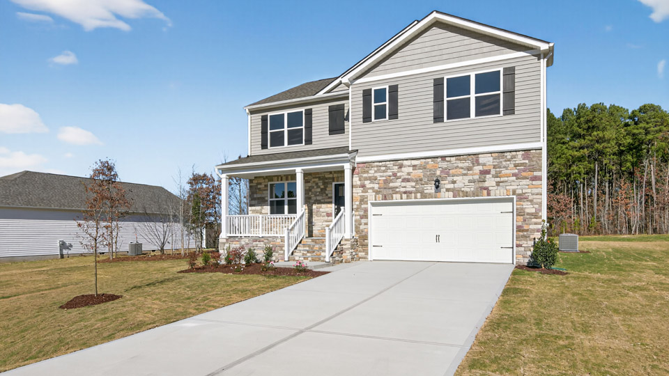 Two story home with gray siding and covered porch and two-car garage.