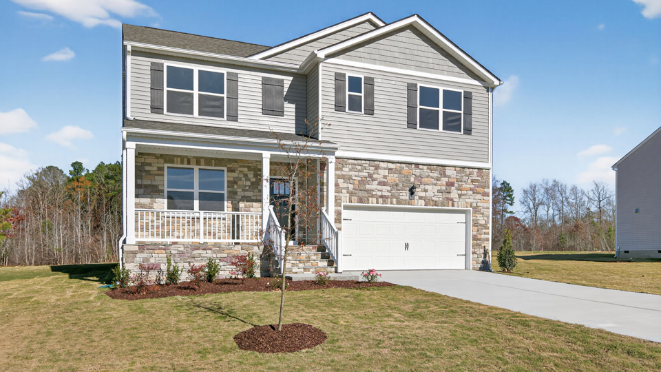 Two story home with gray siding and covered porch and two-car garage.
