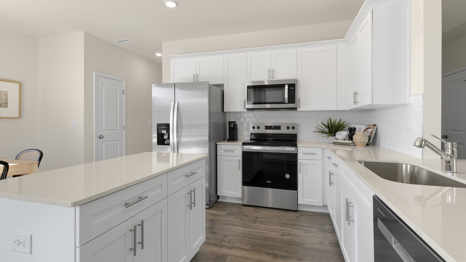kitchen with quartz counters, kitchen island, pantry, stainless steel appliances