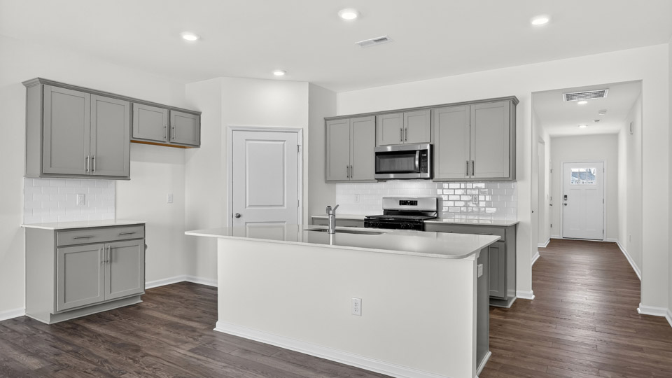 kitchen with quartz counters, kitchen island, pantry, stainless steel appliances