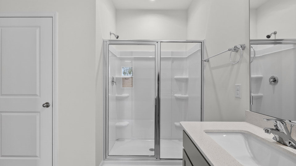 primary bathroom with walk in shower and dual vanity sinks