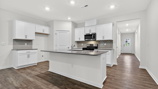kitchen with quartz counters, kitchen island, pantry, stainless steel appliances