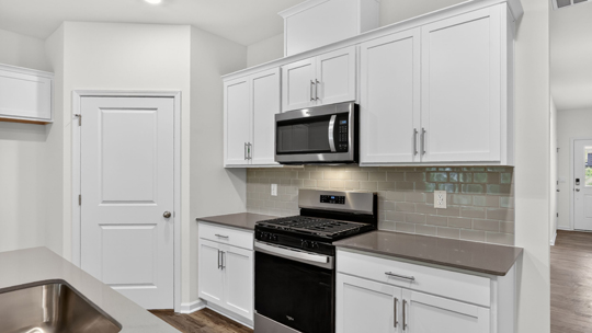 kitchen with quartz counters, kitchen island, pantry, stainless steel appliances