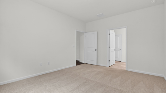 primary bedroom with two windows and carpeting, attached bath