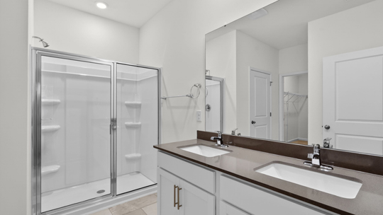 primary bathroom with walk in shower and dual vanity sinks