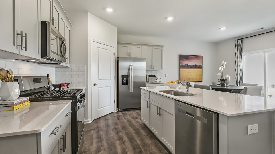 kitchen with quartz counters, kitchen island, pantry, stainless steel appliances