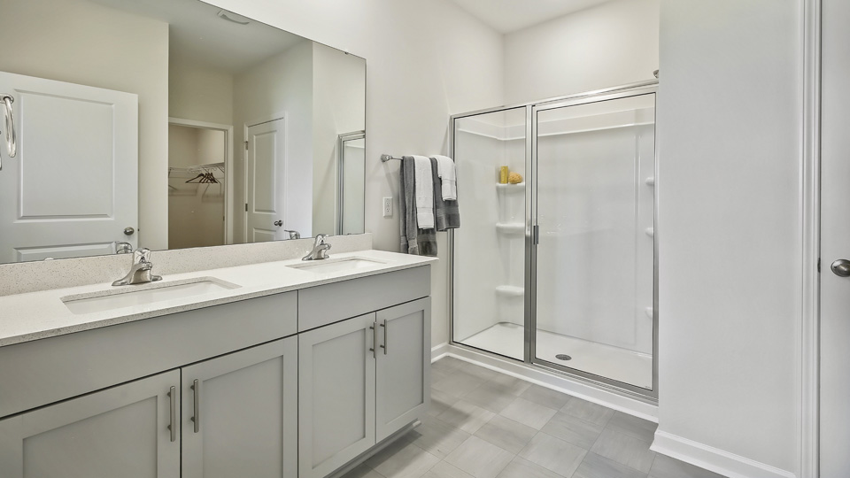 primary bathroom with walk in shower and dual vanity sinks