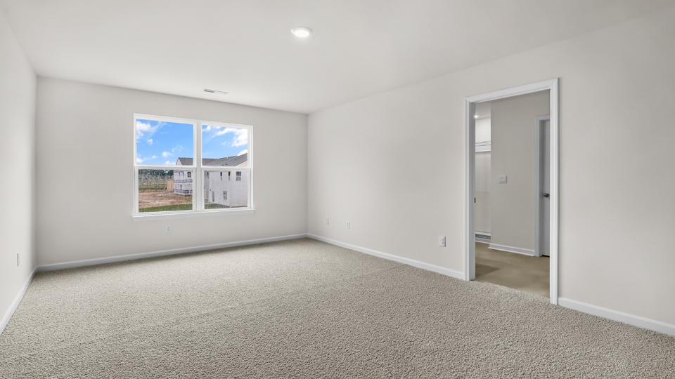 primary bedroom with two windows and carpeting, attached bath