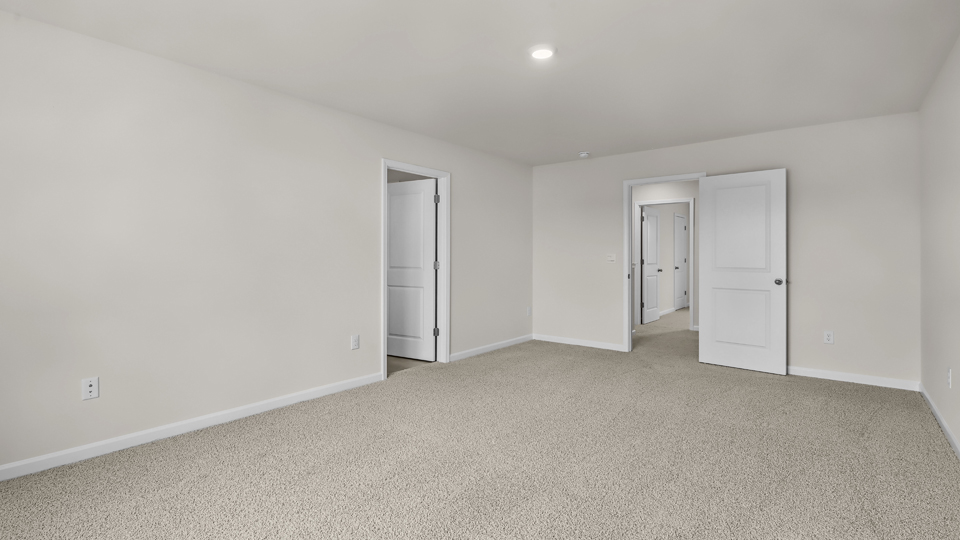 primary bedroom with two windows and carpeting, attached bath