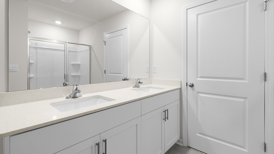primary bathroom with walk in shower and dual vanity sinks