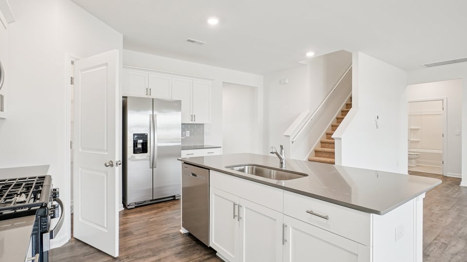 kitchen with quartz counters, kitchen island, pantry, stainless steel appliances