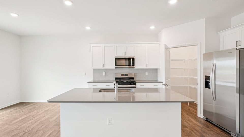 kitchen with quartz counters, kitchen island, pantry, stainless steel appliances