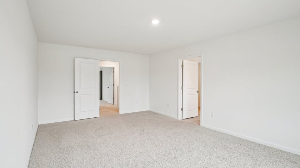 primary bedroom with two windows and carpeting, attached bath