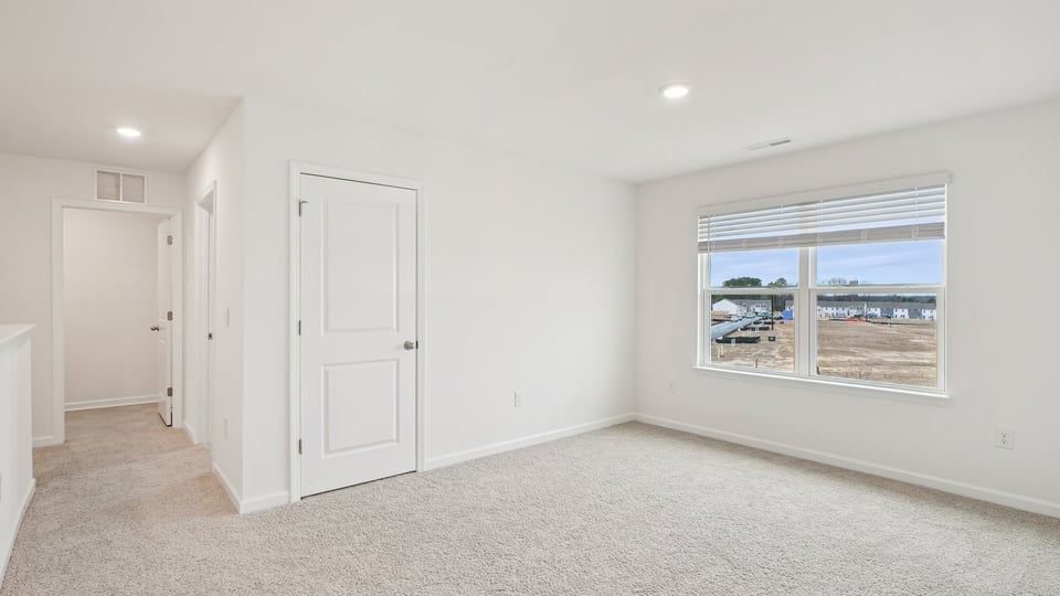 upstairs loft area with large windows and carpeting
