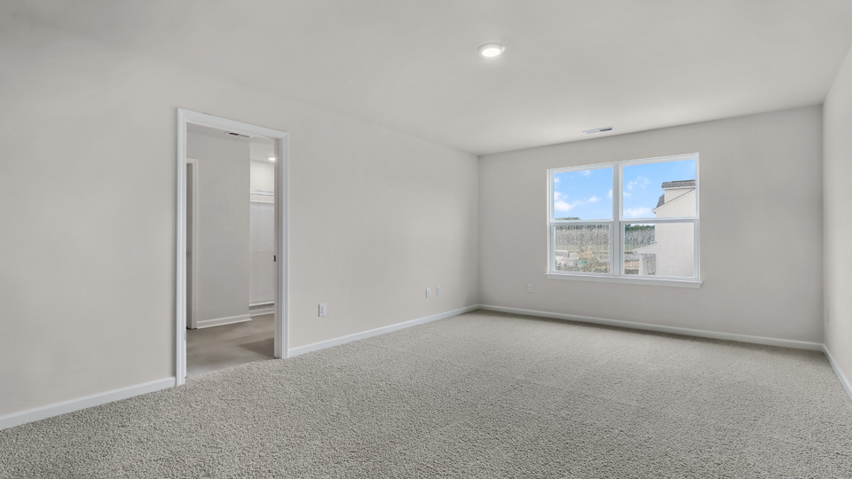 primary bedroom with two windows and carpeting, attached bath