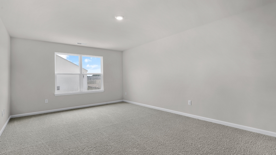 primary bedroom with two windows and carpeting, attached bath