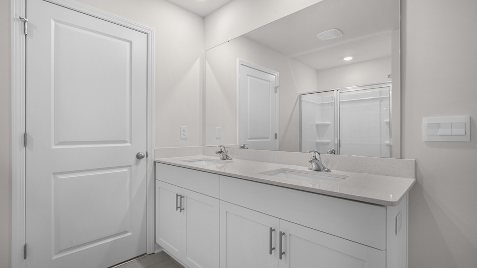 primary bathroom with walk in shower and dual vanity sinks