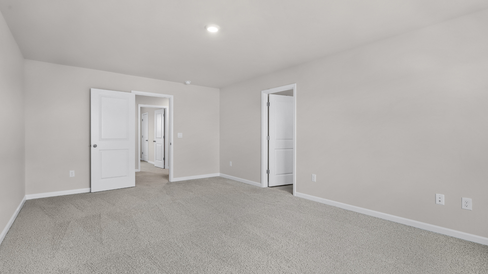 primary bedroom with two windows and carpeting, attached bath