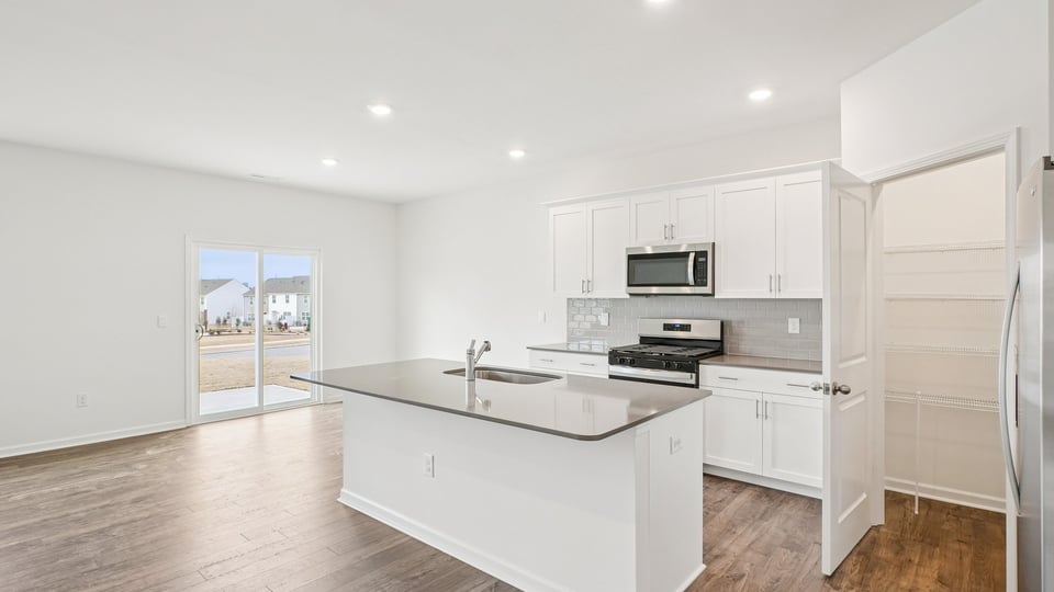 kitchen with quartz counters, kitchen island, pantry, stainless steel appliances