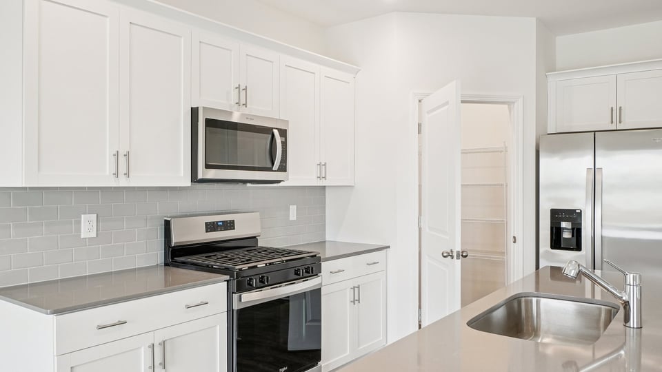 kitchen with quartz counters, kitchen island, pantry, stainless steel appliances
