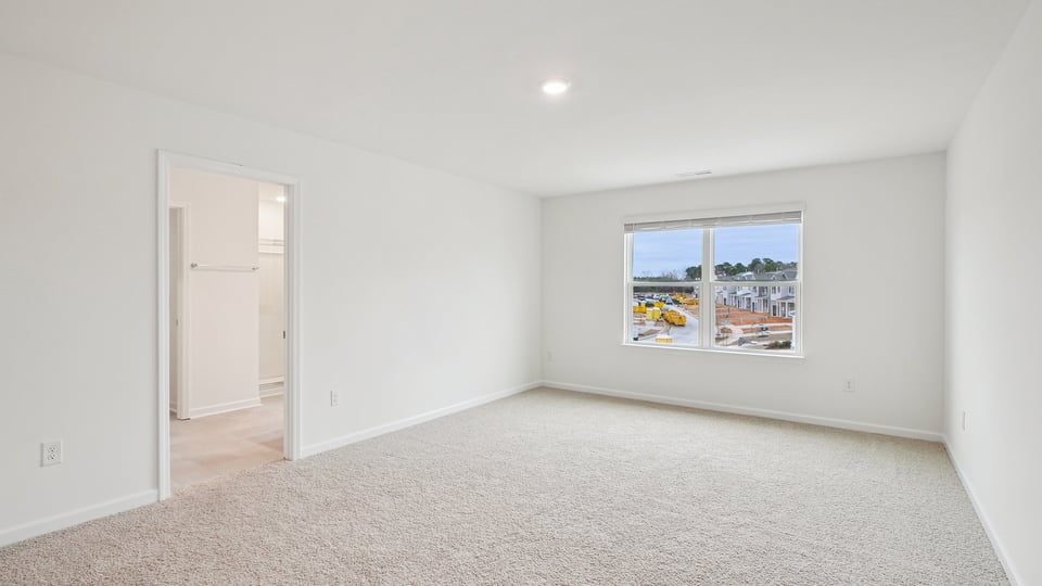 primary bedroom with two windows and carpeting, attached bath