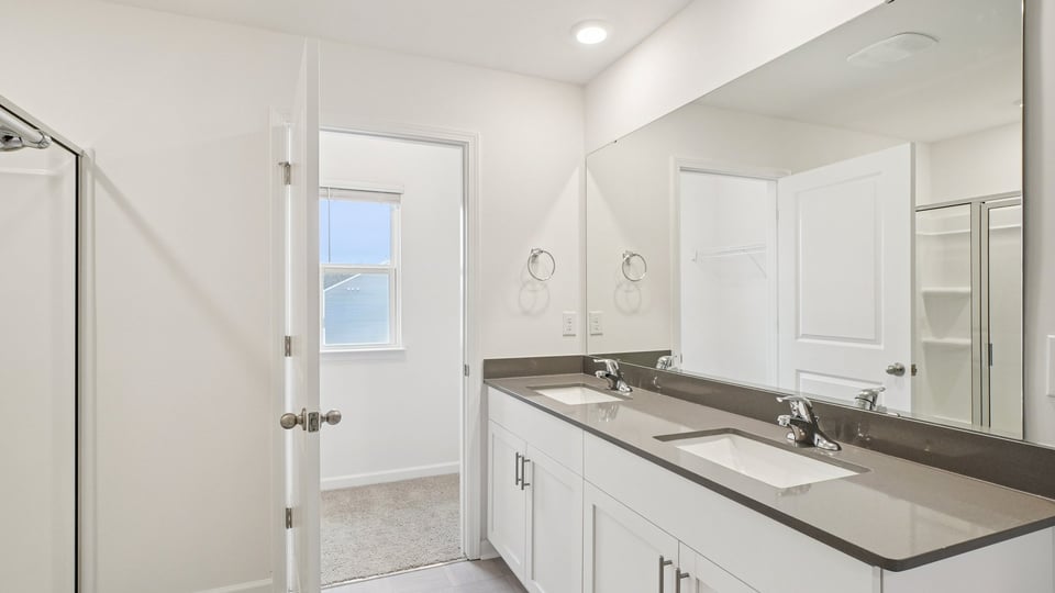 primary bathroom with walk in shower and dual vanity sinks