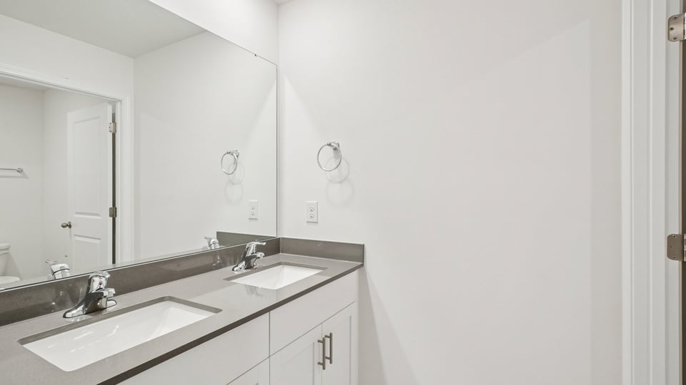 secondary bathroom with shower tub combo and dual vanity sink