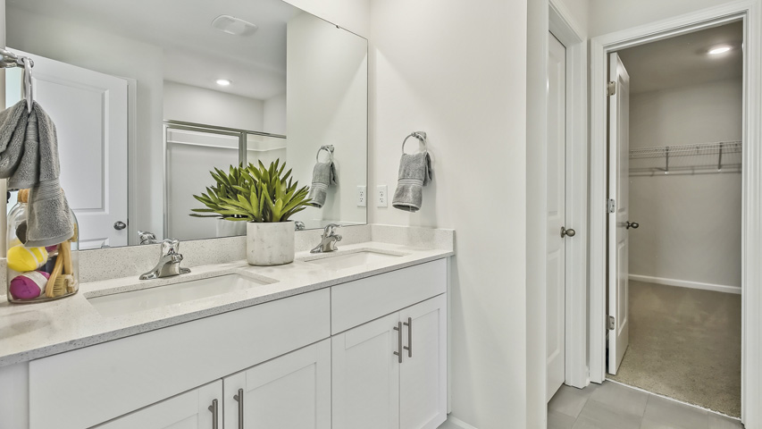 primary bathroom with walk in shower and dual vanity sinks