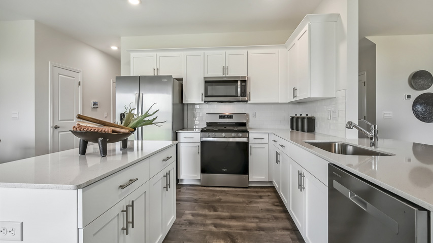 kitchen with quartz counters, kitchen island, pantry, stainless steel appliances