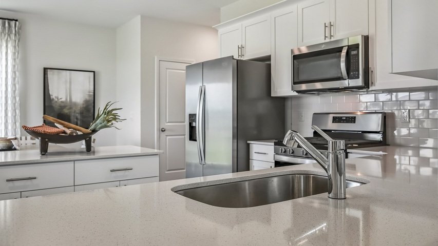 kitchen with quartz counters, kitchen island, pantry, stainless steel appliances