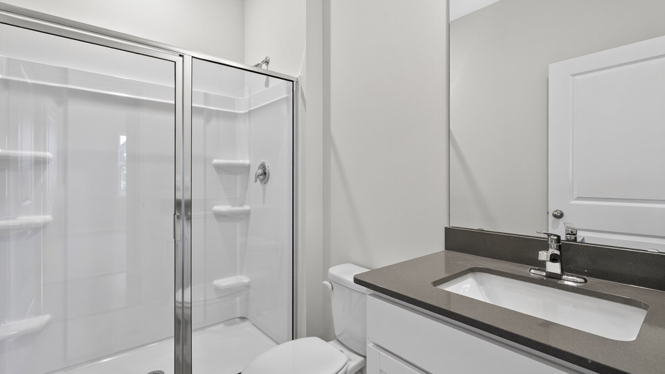 secondary bathroom with walk in shower and single vanity sink