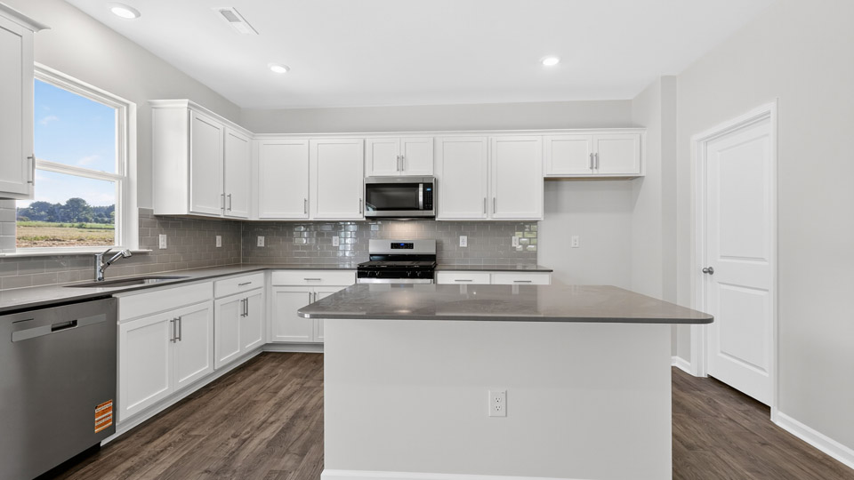 kitchen with quartz counters, kitchen island, pantry, stainless steel appliances