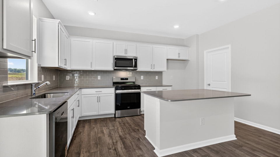 kitchen with quartz counters, kitchen island, pantry, stainless steel appliances