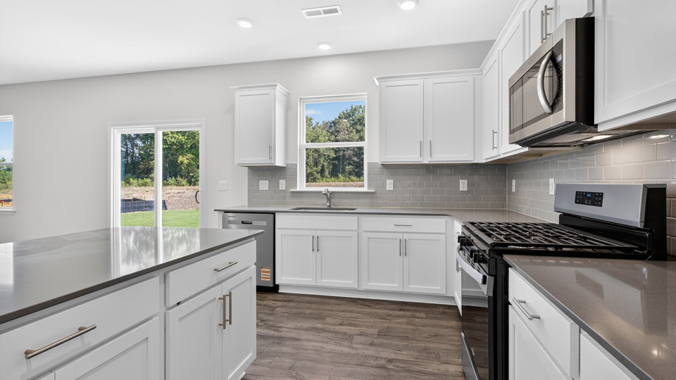 kitchen with quartz counters, kitchen island, pantry, stainless steel appliances