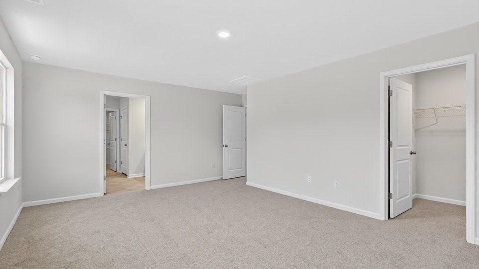 primary bedroom with two windows and carpeting, attached bath