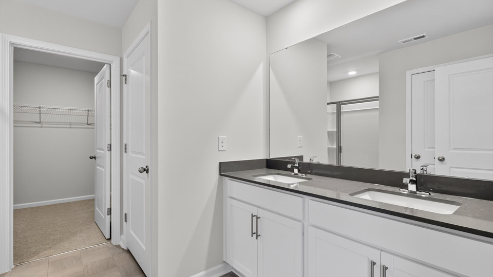 primary bathroom with walk in shower and dual vanity sinks