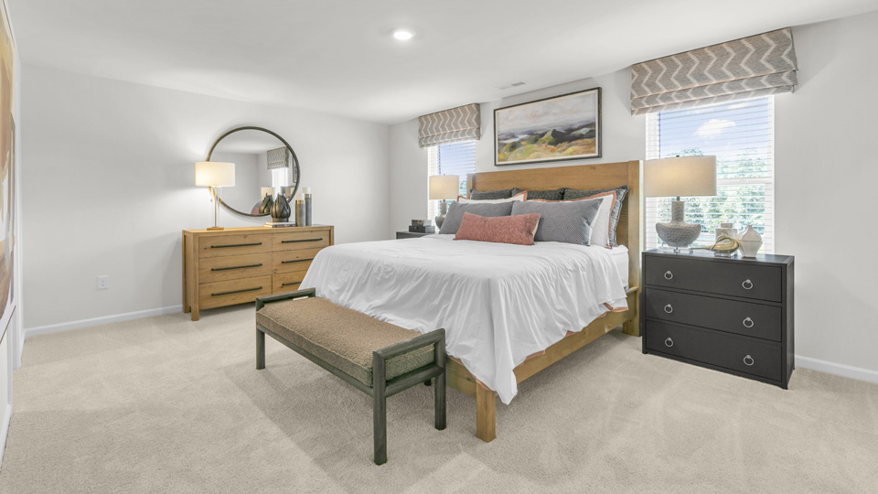 primary bedroom with two windows and carpeting, attached bath