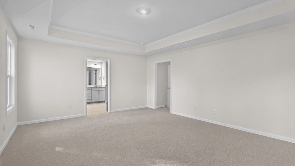 primary bedroom with two windows and carpeting, attached bath