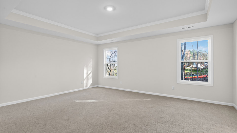 primary bedroom with two windows and carpeting, attached bath