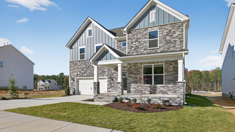 Two story home with blue siding and covered porch and two-car garage.