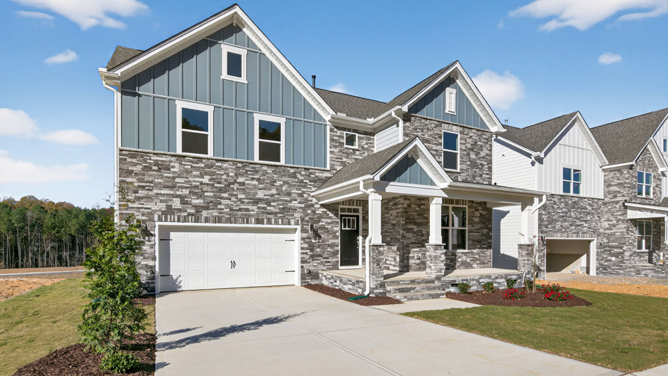 Two story home with blue siding and covered porch and two-car garage.